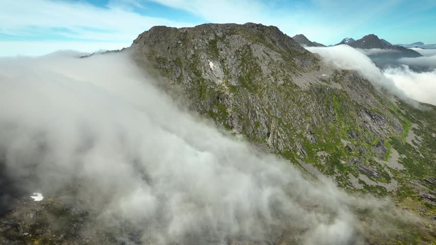 Aerial of of the clouds flowing over a mountain in Norway