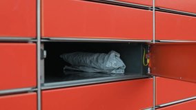 Hand placing a box and envelopes into an orange automated parcel locker for shipment. Close-up of the delivery process and self-service logistics. High quality 4k footage - Powered by Shutterstock - Get 15% off with code: PIKWIZARD15