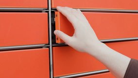 Close-up of a hand opening an orange automated parcel locker to retrieve a cardboard box and mail envelope. Concept of e-commerce delivery and pickup. High quality 4k footage - Powered by Shutterstock - Get 15% off with code: PIKWIZARD15