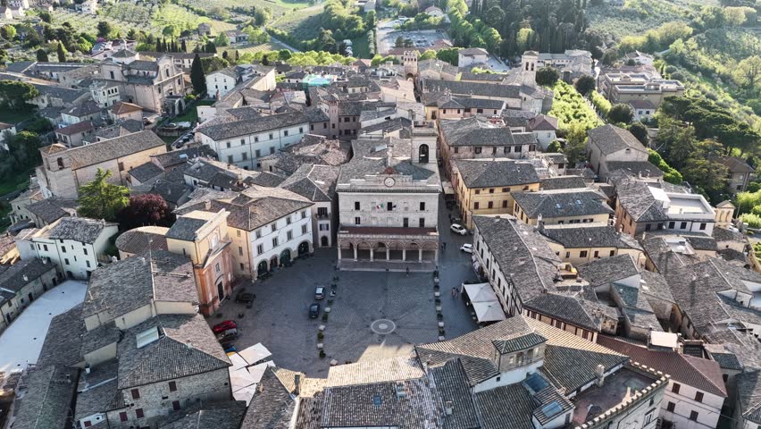 Aerial view of the circular Piazza del Comune surrounded by historic stone buildings and rooftops in Montefalco, Umbria, Italy.