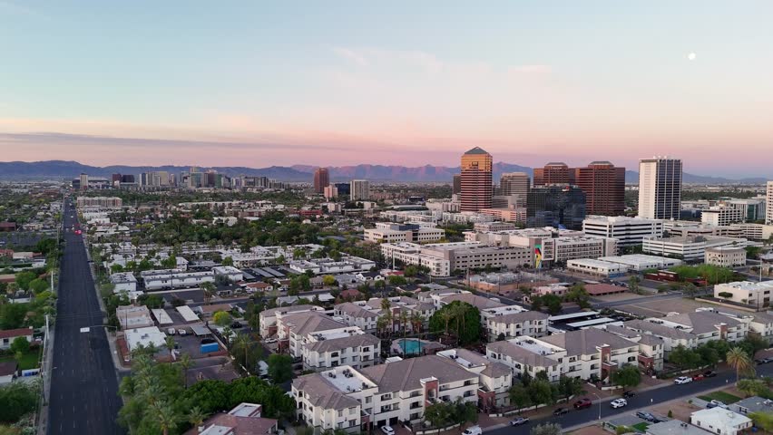 Aerial view of North 7th Street stretching towards the downtown skyline and distant mountains under a sunset sky in Phoenix, Arizona, United States.