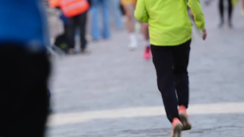 Many people run a race on a paved street during the day.