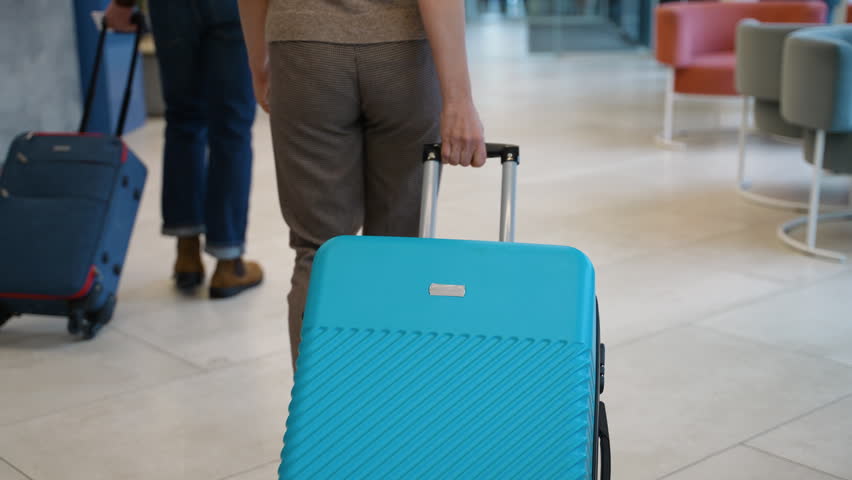 Passengers with rolling luggage walking in airport terminal