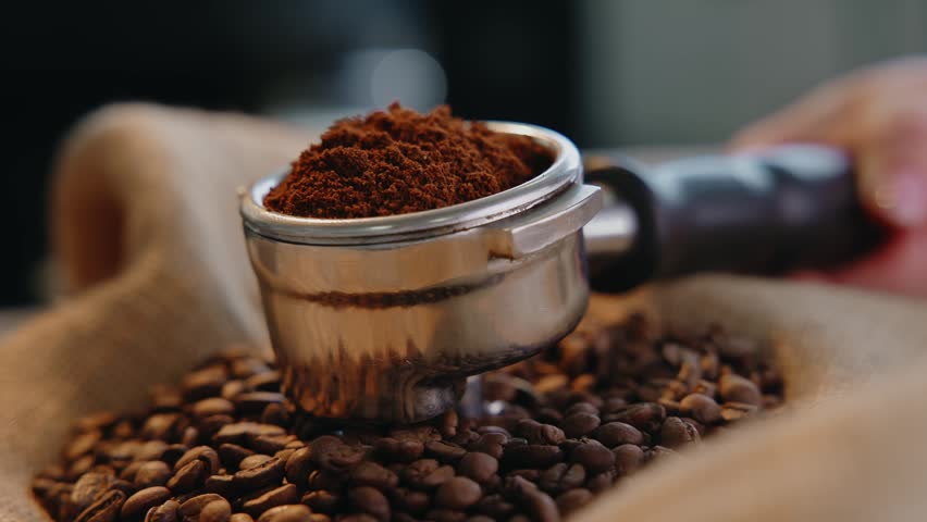 Coffee beans and ground coffee in portafilter on burlap sack background for food banner.