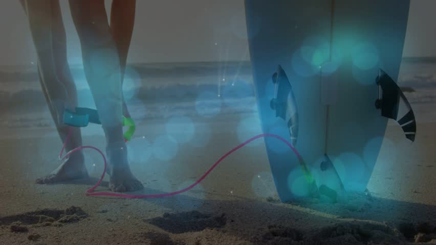 Woman shifting weight by board, grabbing cuff, fastening leash with blue bokeh, preparing to surf. Beach, barefoot, female, surfing, waves, horizon, sunshine