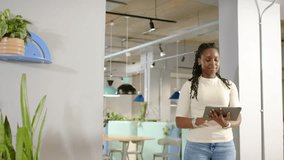 Woman by glass wall in office, tapping tablet opening UI panels and waveforms showing business data. Coworking, workspace, holographic, overlays, touchscreen, partition, modern - Powered by Shutterstock - Get 15% off with code: PIKWIZARD15