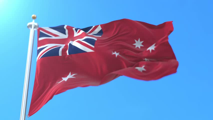 Australian Red Ensign flag waving against a clear blue sky.