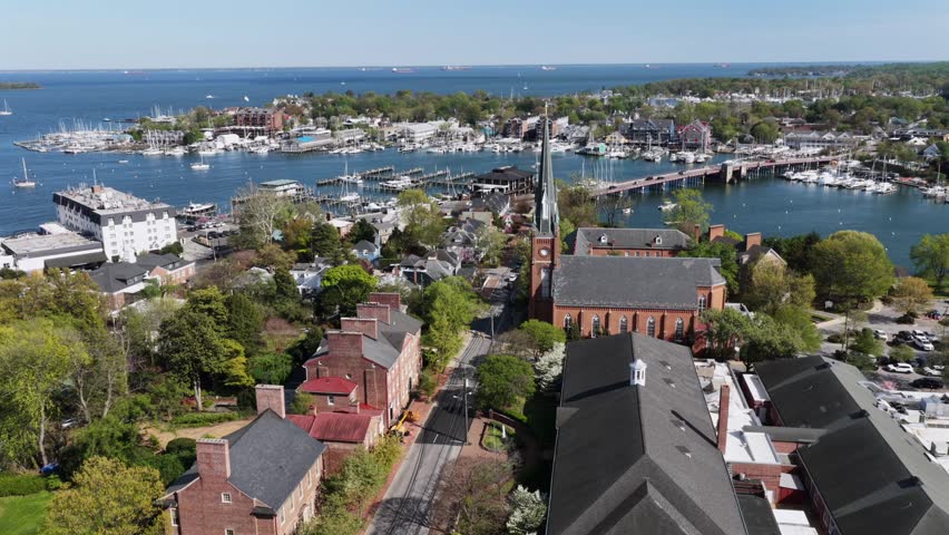 Aerial view of Annapolis, Maryland, USA with church steeple, marina and waterfront bridge, surrounded by historic homes and boats in bright spring sunlight along scenic Chesapeake Bay. Wide shot.