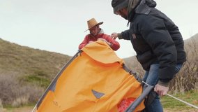 two hikers actively pitching tent, holding fabric and fixing structure, close teamwork and coordination in outdoor environment, concept of cooperation, effort and shared responsibility - Powered by Shutterstock - Get 15% off with code: PIKWIZARD15