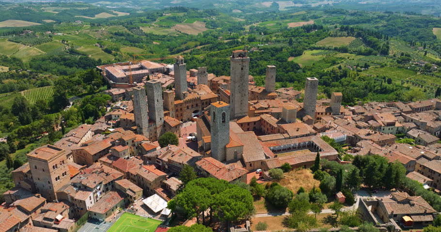 San Gimignano Italy aerial view medieval towers. Historic stone architecture green park trees sunny summer day. Drone shot Tuscany travel destination landmark heritage tourism high angle landscape