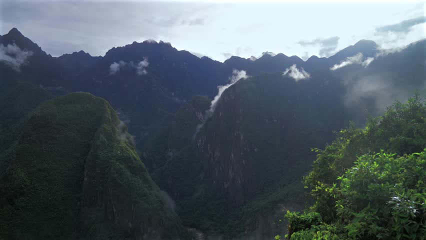 Machu Picchu Pueblo lookout Peruvian Andres highlands jungle Mountains Aguas Calientes Peru landscape early morning sunrise fog layer clouds Inca Trail Temple Vilcanota Urubamba River pan left
