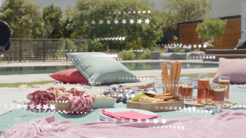Picnic spread sitting pool, camera panning starting star overlay sweeping across food for marketing. Outdoor, backyard, patio, pastel, blankets, pillows, wicker