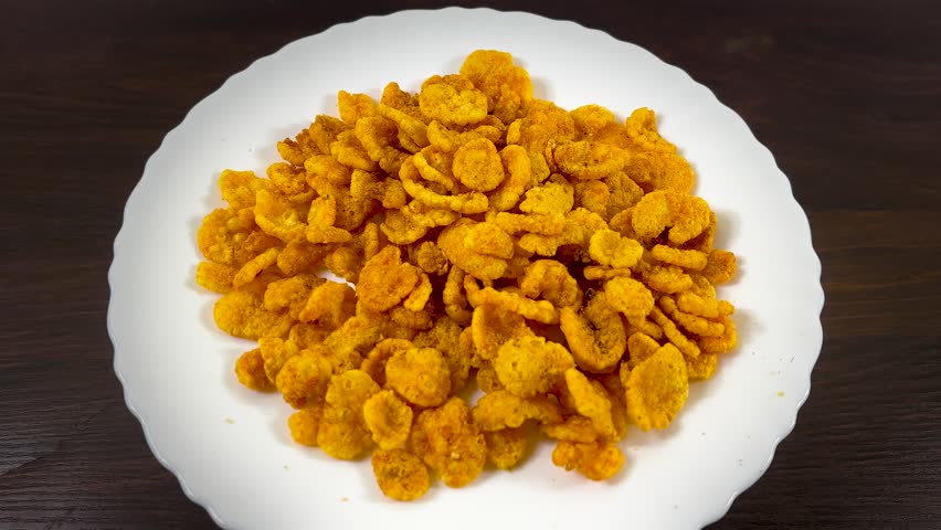 Crunchy corn flakes on white plate, golden cereal breakfast snacks, crispy yellow cornflakes on dark wooden table, healthy morning meal ingredients