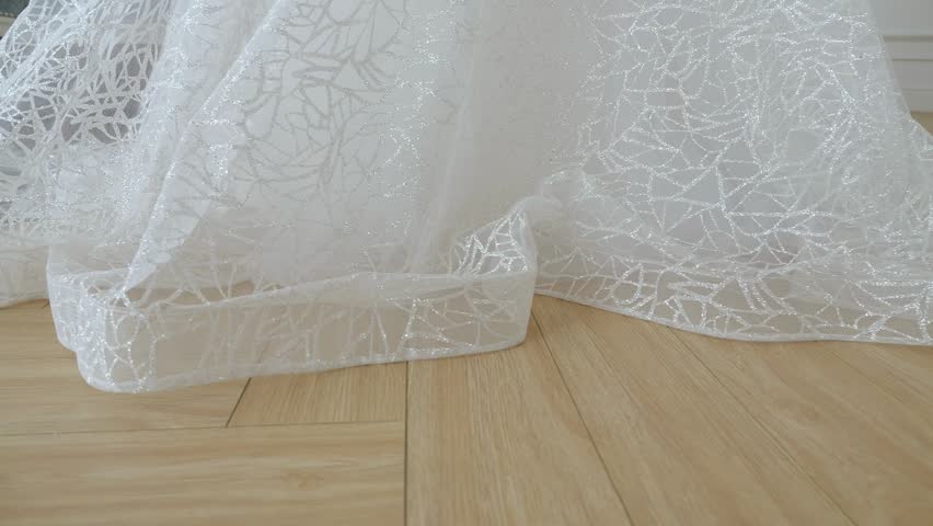 Close-up of the lace hem of a wedding dress. The bride