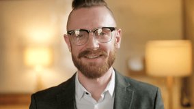 Confident man smiling at camera in a warm modern office portrait. Young male, businessman or professional wearing eyeglasses, formal suit and white shirt, creating a clean corporate image for - Powered by Shutterstock - Get 15% off with code: PIKWIZARD15