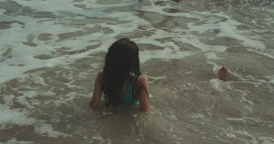 Woman standing in ocean water with waves around body calm coastal lifestyle travel scene