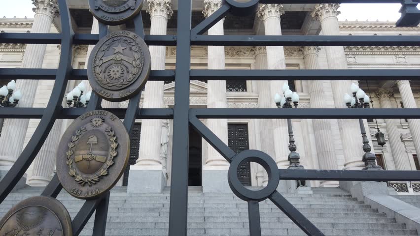 Close-up of the ornate iron gate at the Argentine National Congress in Buenos Aires. Bronze provincial emblems with neoclassical architecture in background. Symbols of Argentine democracy