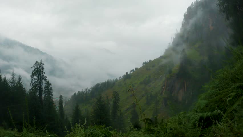 A dramatic stormy sky with dark clouds and rain pouring down over mountain landscape. Moody and atmospheric landscape view. 4K hiker POV during monsoon hike. Travel and holidays background.