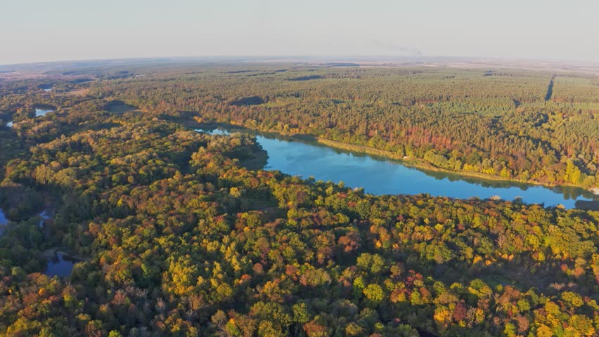 Scenic landscape of lake among lush colorful trees at sunset