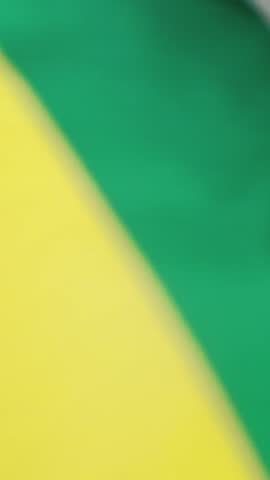 A man walks with a Brazilian flag over his shoulders, seen from behind. A football fan supporting his national team