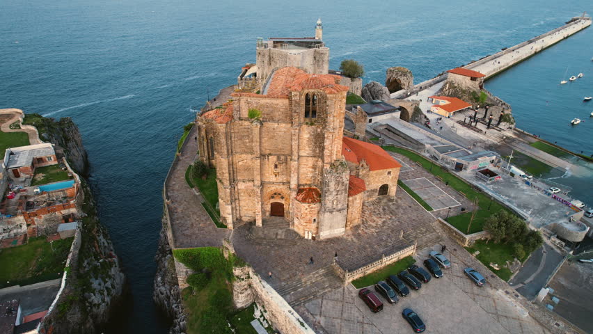 Drone orbiting Santa Maria church in Castro Urdiales revealing harbor, town skyline, boats and coastal horizon. Scenic aerial view of Cantabria northern Spain. High quality 4k footage