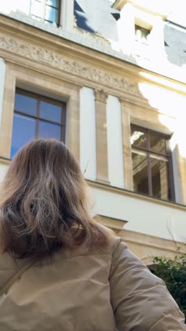 Young woman gazes at decorative facade elements with admiration