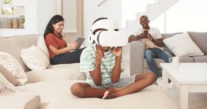 Diverse family watching preteen boy putting on white VR headset, interacting with VR game on couch. Child, visor, virtual, reality, home, livingroom, gaming - Powered by Shutterstock - Get 15% off with code: PIKWIZARD15