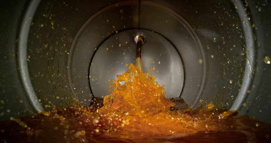 Super slow motion (1000 fps) gasoline pouring into metal fuel tank, dynamic splash and turbulence. Concept of refueling, energy supply and fuel storage, dramatic lighting, industrial environment. Speed ramp.