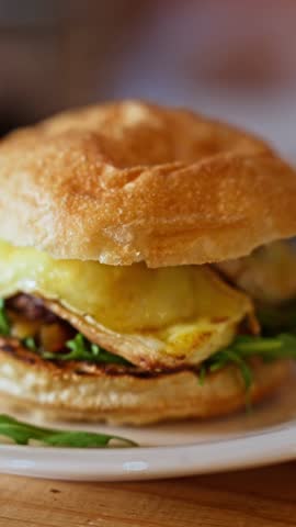 Delicious close up of a fresh bagel burger with melted cheese and arugula on a plate. An appetizing sandwich perfect for lunch or dinner