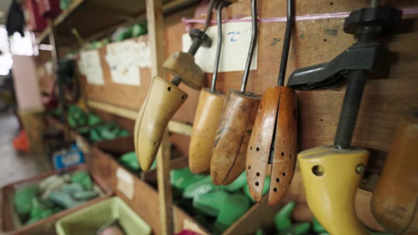 Wooden shoe molds hanging in a workshop in Malaysia. Traditional tools used for shaping footwear highlight craftsmanship, heritage techniques, and artisan production environment.