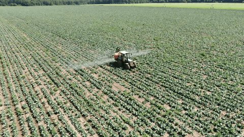 Drone Ascending Backward over Field Spraying Tractor