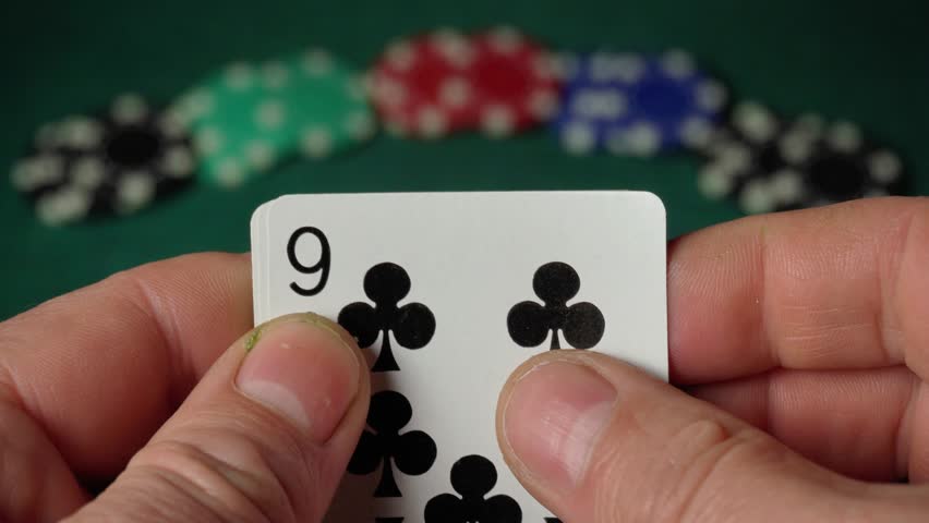 Close-up of hands displaying a sequence of playing cards, including numbers 7 and 9, with colorful poker chips blurred in the background, creating a vibrant gaming atmosphere