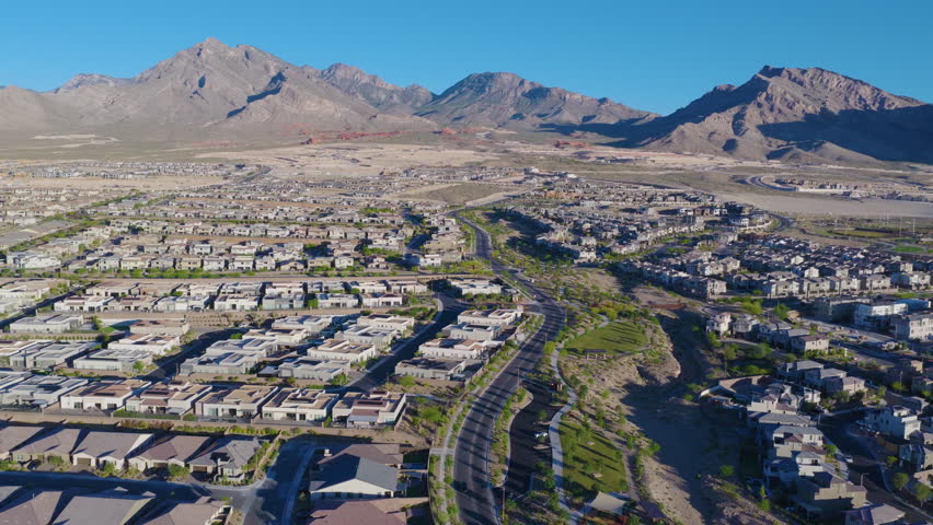 Modern Las Vegas Desert Suburbs Below Rugged Sunlit Mountain Peaks