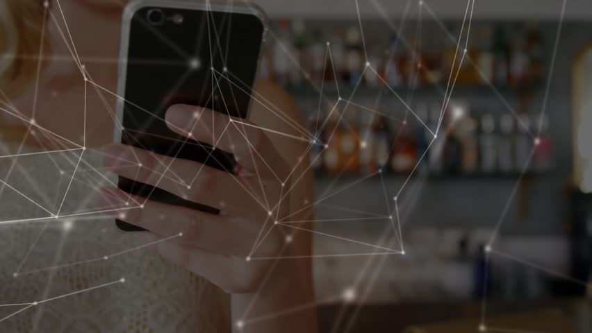 Holding phone, woman in sleeveless top tapping screen at bar with cocktail and network overlay. Device, drink, glass, lime, mint, pub, shelves