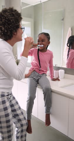 Vertical video: Selecting toothbrush and toothpaste, mother and child brushing teeth at sink. Family, bonding, health, routine, lifestyle, wellness, vertical video