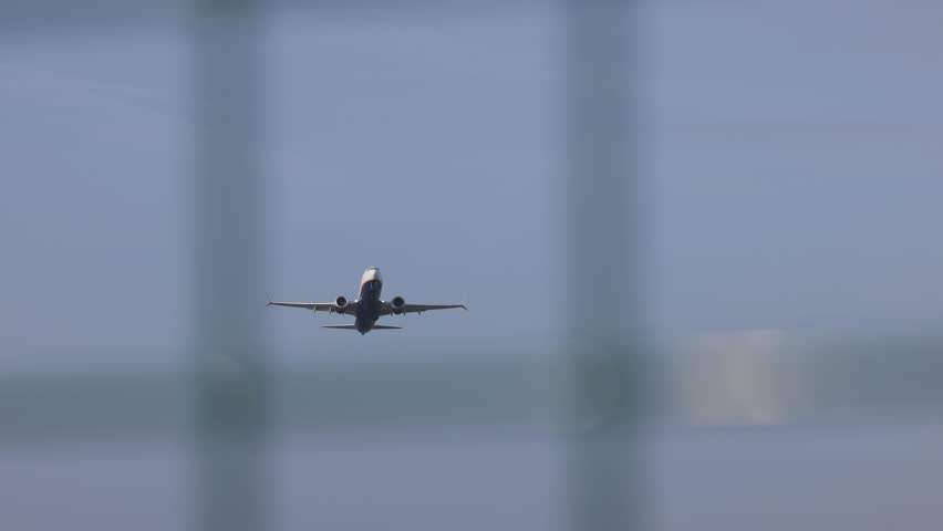 Airplane taking off in Porto airport with fence. Slow motion shot.