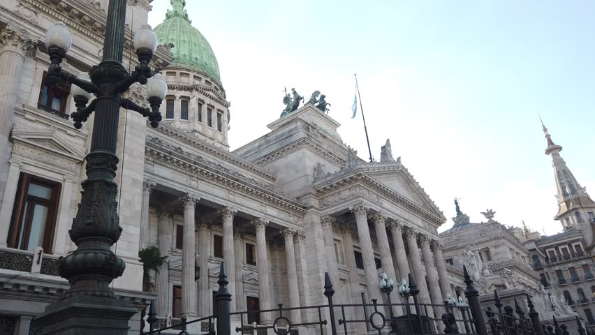 Low angle view of the Argentine National Congress Palace in Buenos Aires. Detailed neoclassical facade, green copper dome, and ornate sculptures under a clear sky. Landmark of Argentina