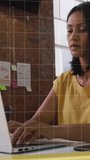 Vertical video: Mature woman typing at desk starting sliding code overlay showing data for analysis. Loft, brick, notes, daylight, focus, technology, vertical video - Powered by Shutterstock - Get 15% off with code: PIKWIZARD15