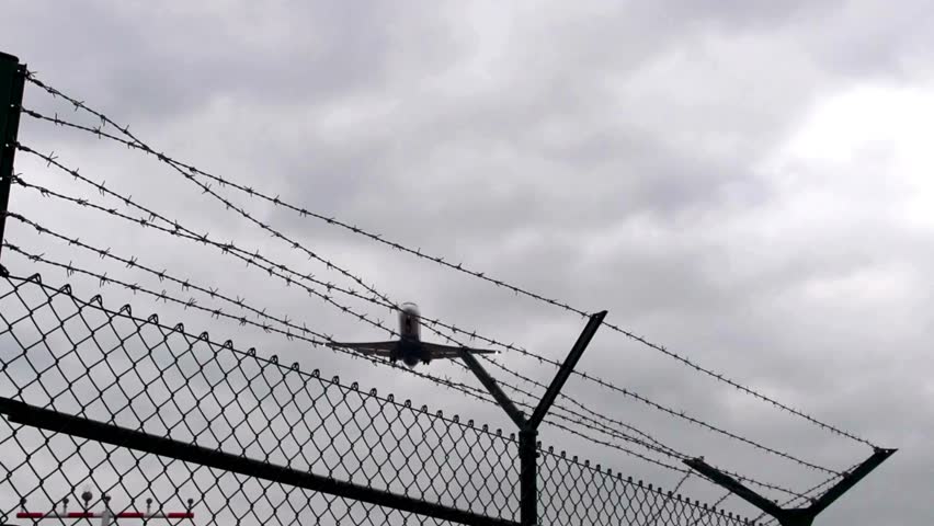 Barbed Wire with plane Moving Shot barbed wire fence boundary barrier restrict prison isolated base at sunset close up. concept of freedom