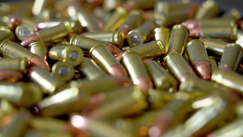 Pile of 9mm bullets rotating clockwise in circular formation. Close up of ammunition cartridges spinning with metallic shine