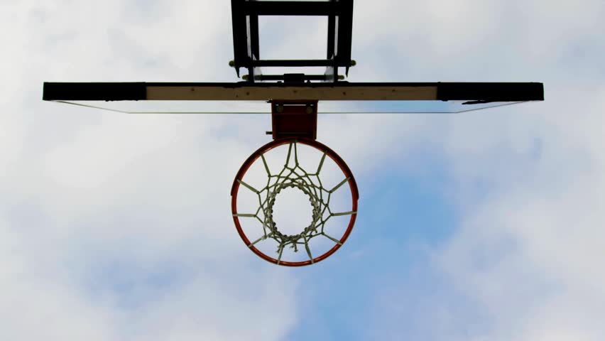 close-up of basketball hoop in an outdoor sports court, view from below. unrecognizable boys playing basketball at playground. outdoor basketball court.
