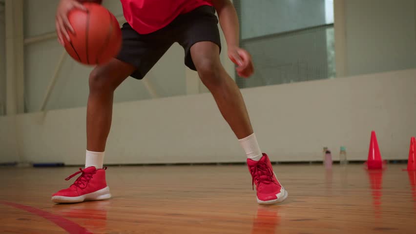 Close video of Basketball players legs during the game practice. Basketball player dribbling ball on indoor court. man training in dribbling basketball.