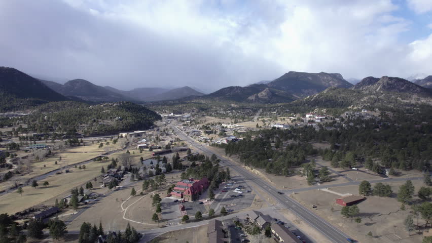wide view of the Rocky Mountains over Estes Park, Colorado, and the road leading to town aerial view