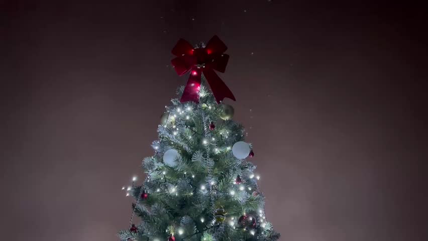 Decorated Christmas tree glowing with twinkling lights against a dark background in a festive evening atmosphere