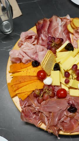 Christmas Dinner - Lavish Charcuterie Board With Prosciutto, Ham, Varied Cheeses, And Crackers. overhead, sliding shot