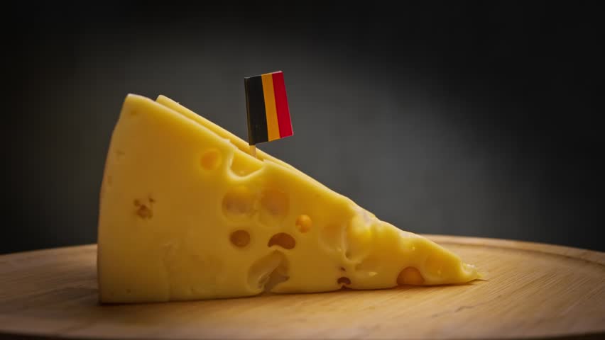 swivel of semi-hard cheese block from Flemish fields, regular air cells on oak stand and Belgium flag, personifying Brussels customs with products from Antwerp markets