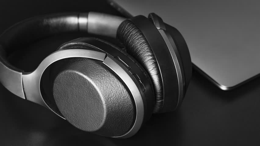 Detailed view of premium audio equipment, showcasing the texture and design of headphones and a sleek laptop in a minimalist setting