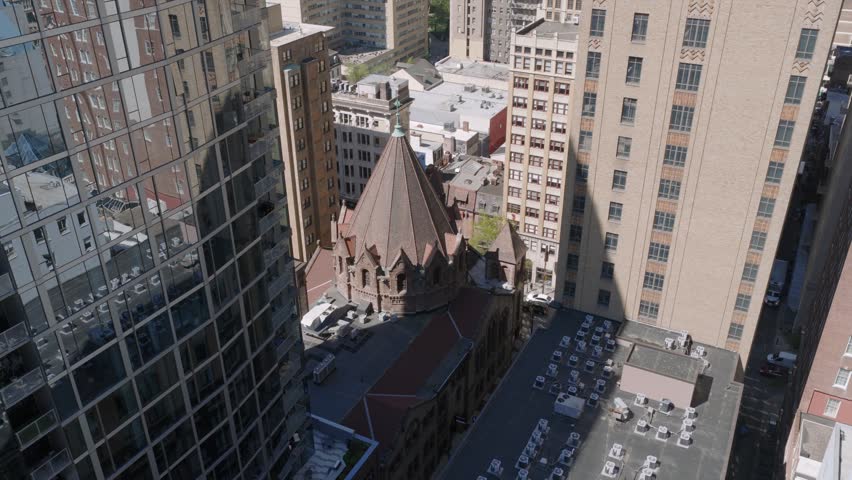 High aerial view of a historic church tower nestled between modern city buildings.