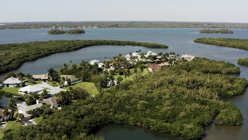 Aerial view of lake with small islands and surrounding green landscape.