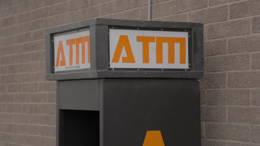 This panning video shows an outdoor ATM machine set against a brick wall.  
